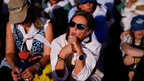 EPA/Shutterstock A woman sits among the crowds in Madrid awaiting the Pope's arrival