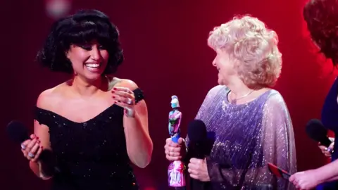 PA Media Raye on stage after winning the award for Song of the Year during the Brit Awards, with Jo Hamilton