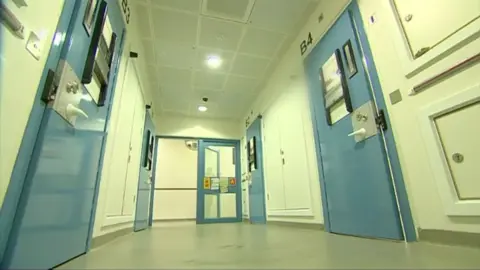 BBC East The interior of a police station showing a corridor with doors leading to custody cells