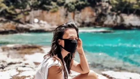 Getty Images Woman on beach wearing mask