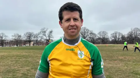 Man with short brown hair in yellow and green GAA top