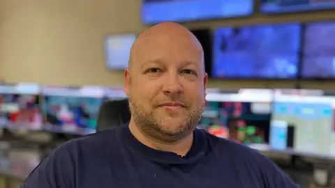 A head and shoulders shot of Melton Renewable Energy CEO, Eddie Wilkinson. He is wearing a navy blue t-shirt and looking directly into the camera.
