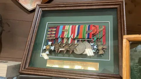 A collection of Blair Mayne's medals. The nine medals are displayed in brown wooden frame behind glass.
