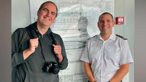 George Holland George Holland and the captain in front of a diagram showing the layout of the ship
