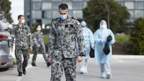 EPA A soldier wearing a mask walks out of a nursing home with other medical responders