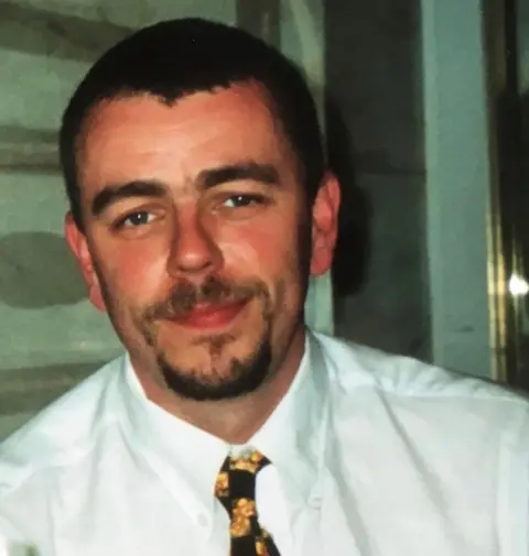 Alison/UCPI A man is looking at camera whilst wearing a white shirt and tie. He has dark hair and facial hair