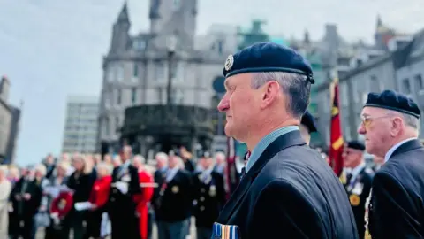 Aberdeen ve day crowds wearing military uniform and medals carrying flags