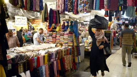 EPA An Iraqi woman walks through a market in eastern Mosul, northern Iraq (14 August 2017)