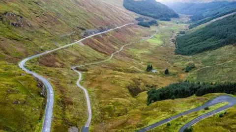 Transport Scotland An aerial view of the Old Military Road, stretching through grassy hills and mountains 