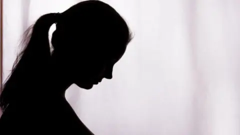 Getty Images A woman can be seen in silhouette looking down in this generic photo.
