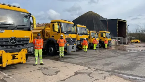 Suffolk County Council A row of gritters and Melton gritting team. 