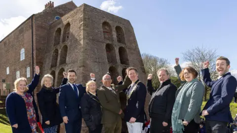 NWLDC A line of VIPs gathered in a line to celebrate at a blast furnace that is now a museum