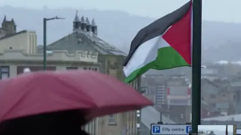 A Palestinian flutters outside a business on Leeds Ro