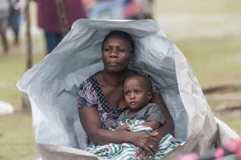 AFP People gather after spending the night outside after facing the severe inclement weather of Tropical Storm Grace near Les Cayes, Haiti on 17 August 2021
