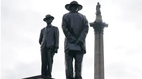 PA Media A statue at Trafalgar Square, depicting two men dressed in suits and hats