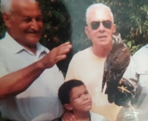 Maher Mezahi Two older men with a young boy looking at a bird