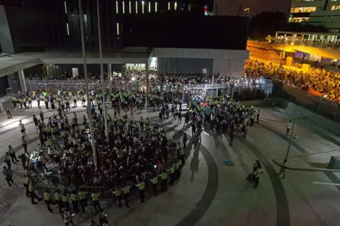 AFP/Getty Images Student pro-democracy demonstrators are surrounded by police after storming into a courtyard outside Hong Kong's legislative headquarters on 26 September 2014.