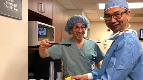 Teoh family Professor Lew Schon, Professor of Orthopaedics, Johns Hopkins School of Medicine with Dr Kar Hao Teoh. Both are wearing surgical scrubs.