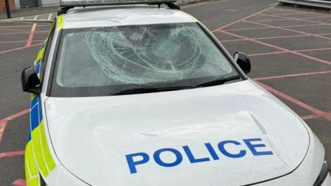 A police car with a damaged windscreen and bonnet