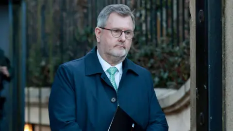 PA Media Sir Jeffrey Donaldson, with short grey hair, wearing glasses, a white shirt, light blue tie and navy jacket. 