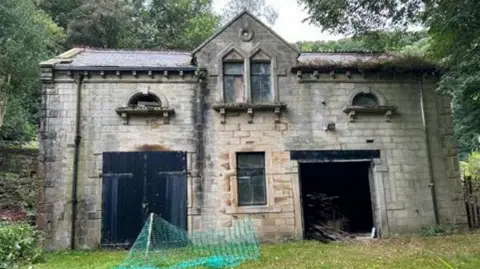 Local Democracy Reporting Service An old dilapidated brick building is surrounded by trees.