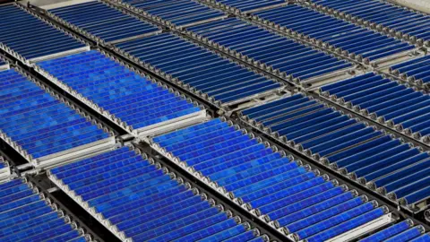 Naked Energy Rows of blue solar collectors on the roof.