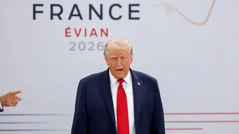 Trump in front of a wall with the words 'France Évian 2026'