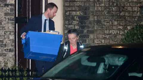 Reuters Police officers carrying a blue box of evidence outsides Mandelson's home