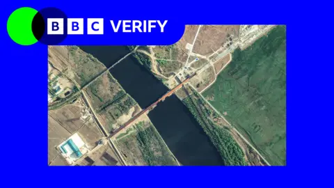 An annotated satellite image taken on 6 May showing the new road bridge and the existing rail bridge. It is imposed over the BBC Verify colours and branding. 