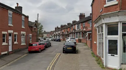 Cope's Avenue in Tunstall. We can see a number of cars and some residential properties. There are terraced homes and vehicles parked on either side of the road. 