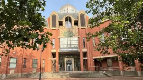 Hull's Combined Court Centre - a large, red brick building, with steps leading up the doors and trees on either side