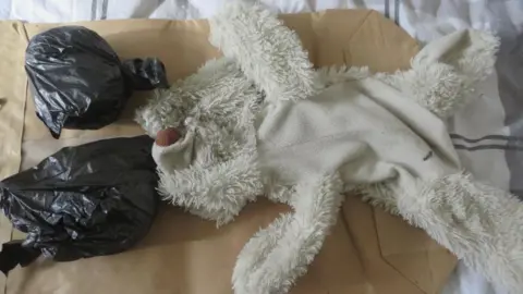 Nottinghamshire Police A white teddy bear next to black bags containing drugs