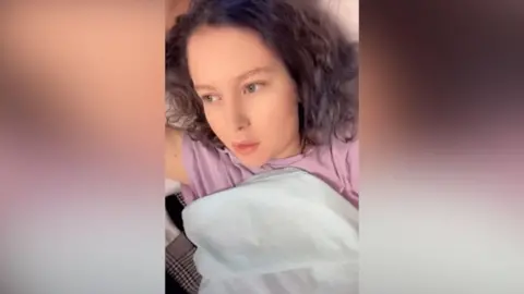 Keeleigh Goodwin A young girl in a hospital bed. She has wavey hair. 