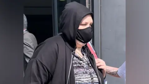 PA Media Holly Le Gresley wearing a black Covid-style face mask walking out of court in a black hoodie