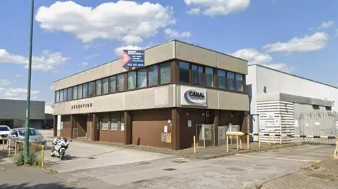 Google A flat-roofed industrial building with offices at the front and a warehouse behind