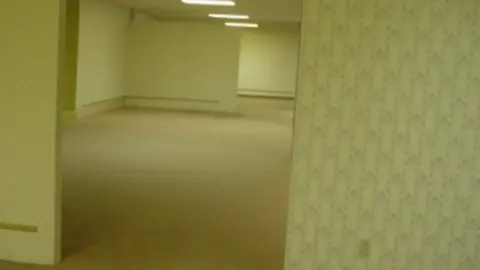 4chan The original image uploaded for the Backrooms, showing abandoned segmented walls and rooms, with mustard yellow wallpaper