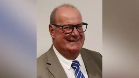 A man in a suit posing for a headshot