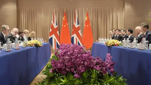 Reuters British Prime Minister Keir Starmer attends a bilateral meeting with President Xi Jinping - their teams sit opposite each other, with UK and Chinese flags between them