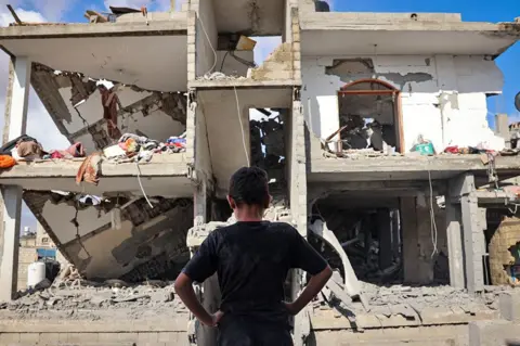 AFP A Palestinian youth stands in front of a destroyed building following Israeli bombardment of Rafah's Tal al-Sultan district in the southern Gaza Strip on 7 May 2024