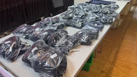 George King/BBC A table with  bagged-up school uniform items on it
