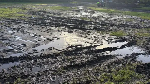 Ben Fryer/BBC There a large areas of mud and water in a park.