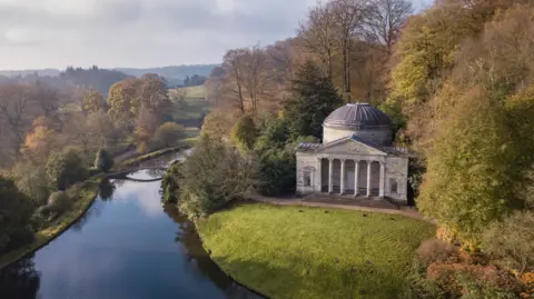 National Trust Images - Mike Calnan A beautiful lake with a thin bridge crossing. In the corner is an old temple style building with pillars