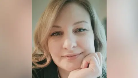 PA Media Picture of Igna Rublite looking directly into the camera and smiling while resting her head on her left hand