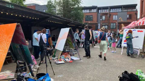 People gathered outside with canvases and art materials