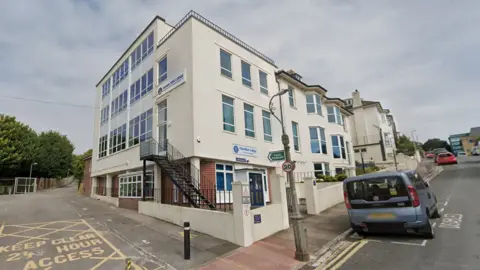 A four-storey white building with signs on the front and side which say "Hamilton Lodge".