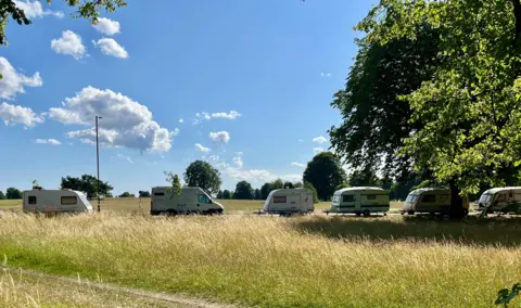 Six caravans parked on the road running through the Downs in Bristol. It is a sunny day with blue skies.