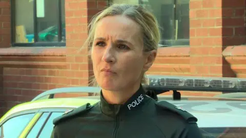 PSNI Ch Supt Gillian Kearney , dressed in uniform, stands i front of a police car