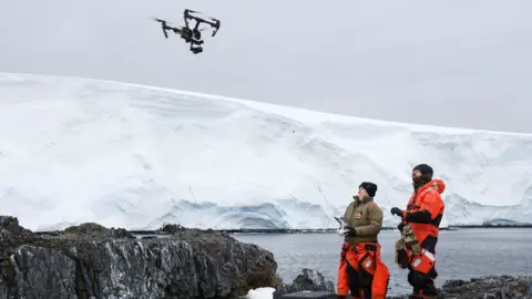 Royal Navy Sailors flying drones in front of the ice