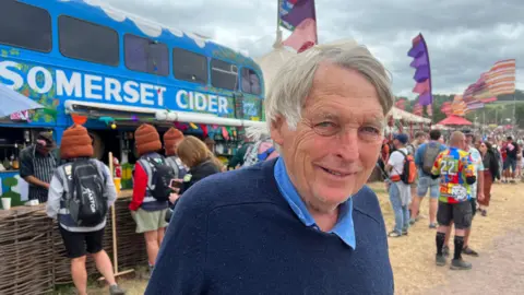 Man stood in front of big blue bus saying 'Cider Bus'