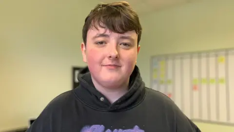 A young man in a black hooded top with dark hair